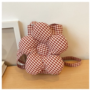 Gros plan d'un sac à bandoulière matelassé à carreaux rouges et blancs en forme de fleur