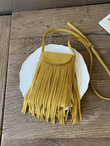 Retro yellow suede tassel crossbody bag for women with bohemian fringe on white plate