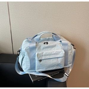Close-up of a light blue nylon travel bag with handles and adjustable shoulder strap