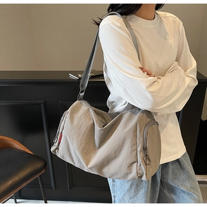 Detail view of khaki canvas tote with side zipper pocket and red label accent