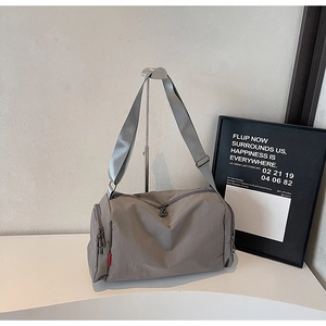 Macro view of grey nylon travel bag showing a side zipper pocket and red label detail
