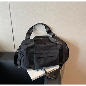Detail of black canvas travel bag featuring durable side drawstring pocket and shoulder strap