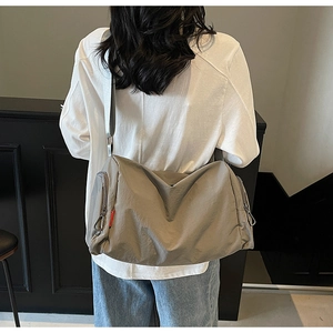 Rear view of model wearing a large canvas crossbody bag with adjustable wide shoulder strap