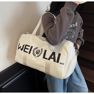 White canvas sports gym bag with large capacity and logo shown carried by a model