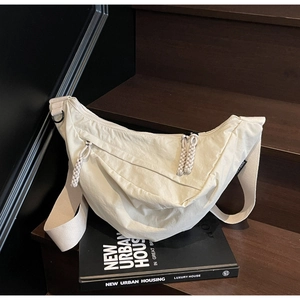 Detailed macro view of off-white nylon dumpling bag with woven zipper and strap