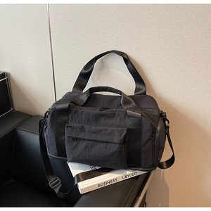 Close-up of black travel duffle bag with adjustable straps and front zipper pocket