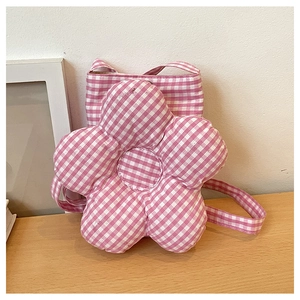 Détail du sac bandoulière en forme de fleur à carreaux rose et blanc sur table en bois