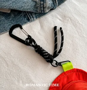 Detail of red nylon coin pouch with black carabiner and leopard rope on denim jacket