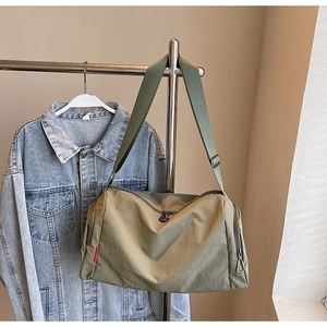 Detail of army green travel bag with adjustable strap and side zipper on a metal hanger