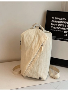 Versatile beige nylon backpack with diagonal zipper on marble surface in minimalist style
