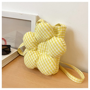 Détail d'un sac bandoulière matelassé jaune à carreaux en forme de fleur douce