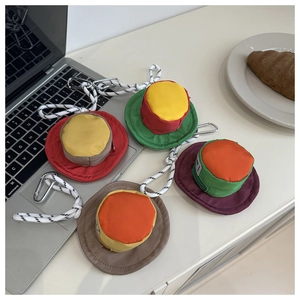 Set of four mini cap-shaped earphone pouches with zippers and carabiners on a white desk
