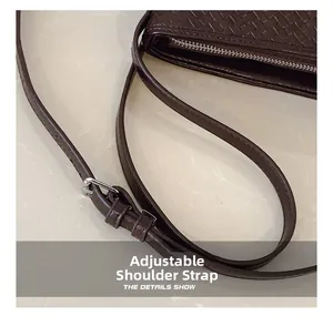 Detail of adjustable shoulder strap with silver buckle on dark brown woven bucket bag