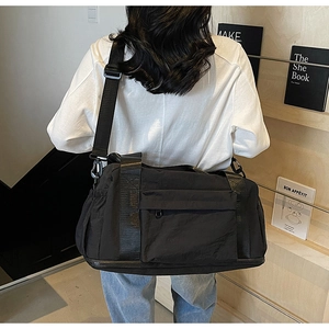 Detail of black large capacity canvas travel bag with side pockets and sturdy straps