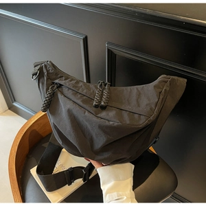 Close-up of black nylon dumpling bag with woven zipper pull and adjustable strap