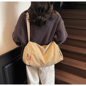 Detailed back view of a beige canvas crossbody bag with side zipper and silver buckle
