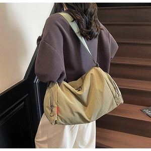 Detail of khaki nylon crossbody bag with wide shoulder strap and silver metal zipper