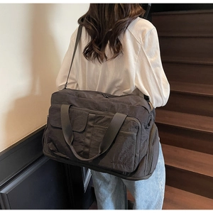 Close-up of charcoal grey travel bag featuring front zip pockets and durable nylon texture
