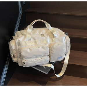 Dettaglio della borsa da viaggio in nylon beige con tasche multiple su scale in legno