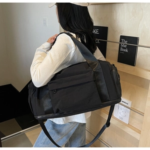 Close-up of black travel bag showing front zipper pocket and wide straps for durability