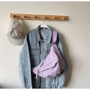 Detail of light purple dumpling bag on a denim jacket with woven rope zipper pull