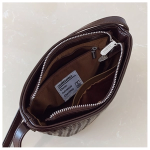 Internal view of the woven bucket bag showing zipper pocket and brown fabric lining