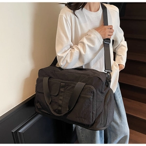 Detail of a large black travel bag with dry-wet separation on a person's shoulder