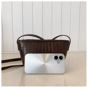 Detail of dark brown woven bucket bag next to a smartphone showing compact size