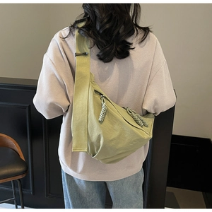 Detail showing smooth light green nylon surface and dual woven rope zipper pulls of crossbody bag