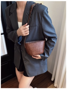 Detail of a brown woven crossbody bucket bag styled with a grey casual business blazer