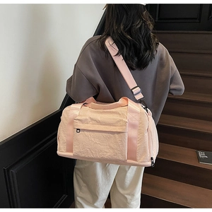 Model wearing peach pink travel bag with separate shoe compartment and adjustable strap
