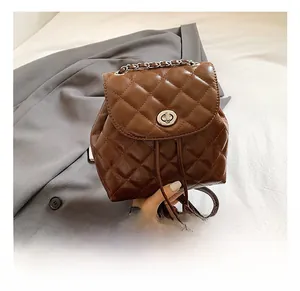 Detail of quilted brown leather backpack with silver chain handle and metallic twist lock