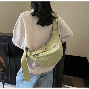Detail of pistachio green dumpling bag featuring thick knotted zippers and wide strap