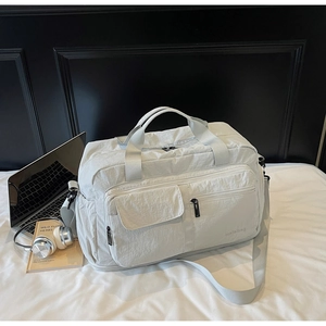 Close-up of lightweight off-white travel bag with functional compartments and waterproof nylon
