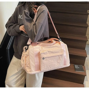 Detail of pink canvas travel bag with adjustable strap and multiple storage pockets
