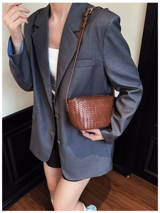 Detailed view of brown woven texture on a compact bucket bag worn with a gray blazer