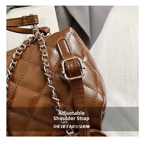 Detail showing the adjustable silver buckle strap on a quilted coffee brown backpack