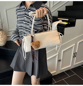 Close-up of a white leather baguette bag featuring embossed lettering and ribbon details