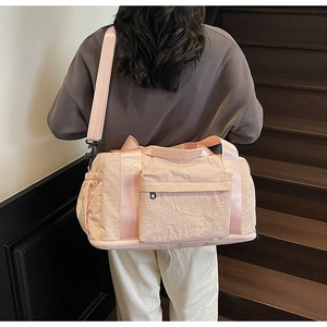 Detail showing the bottom shoe compartment and side drawstring pocket of the pink travel bag