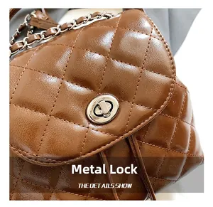 Detail of the silver metal rotating lock and quilted texture on the brown leather bag