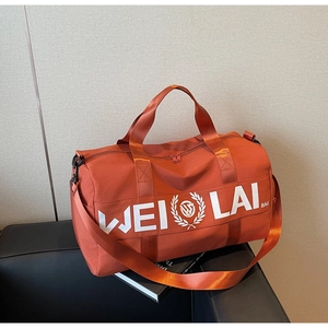 Close-up of orange sports bag with dual handles and logo detail on a display stand