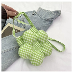 Détail d'un sac bandoulière en forme de fleur à carreaux verts et blancs sur une veste