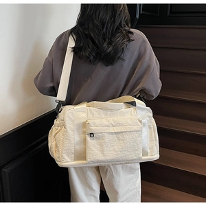 Detail view of large cream canvas travel bag with expandable bottom and shoulder strap