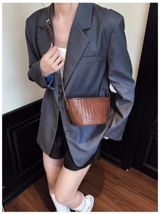 Close-up of brown woven texture on a stylish bucket bag worn with a casual gray blazer