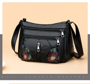 Detail of vintage black leather bag featuring floral embroidery and multi-layer zippers