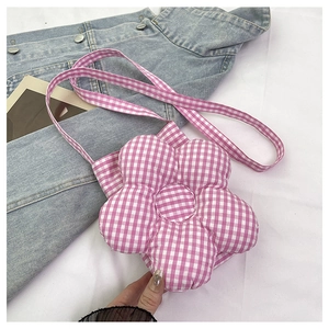 Détail du sac bandoulière en forme de fleur vichy rose sur une veste en jean