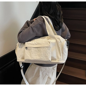 Detail of off-white canvas travel bag featuring side zipper pocket and dual shoulder straps