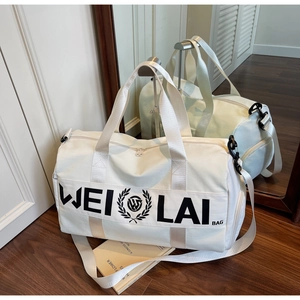 Detail of white large-capacity sports gym bag with logo on dark wood floor