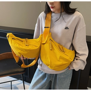 Detail of yellow nylon crescent crossbody bag with woven zipper pull and adjustable strap
