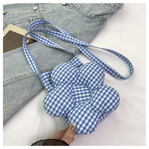 Vue détaillée du sac bandoulière bleu à carreaux en forme de fleur avec tissu matelassé